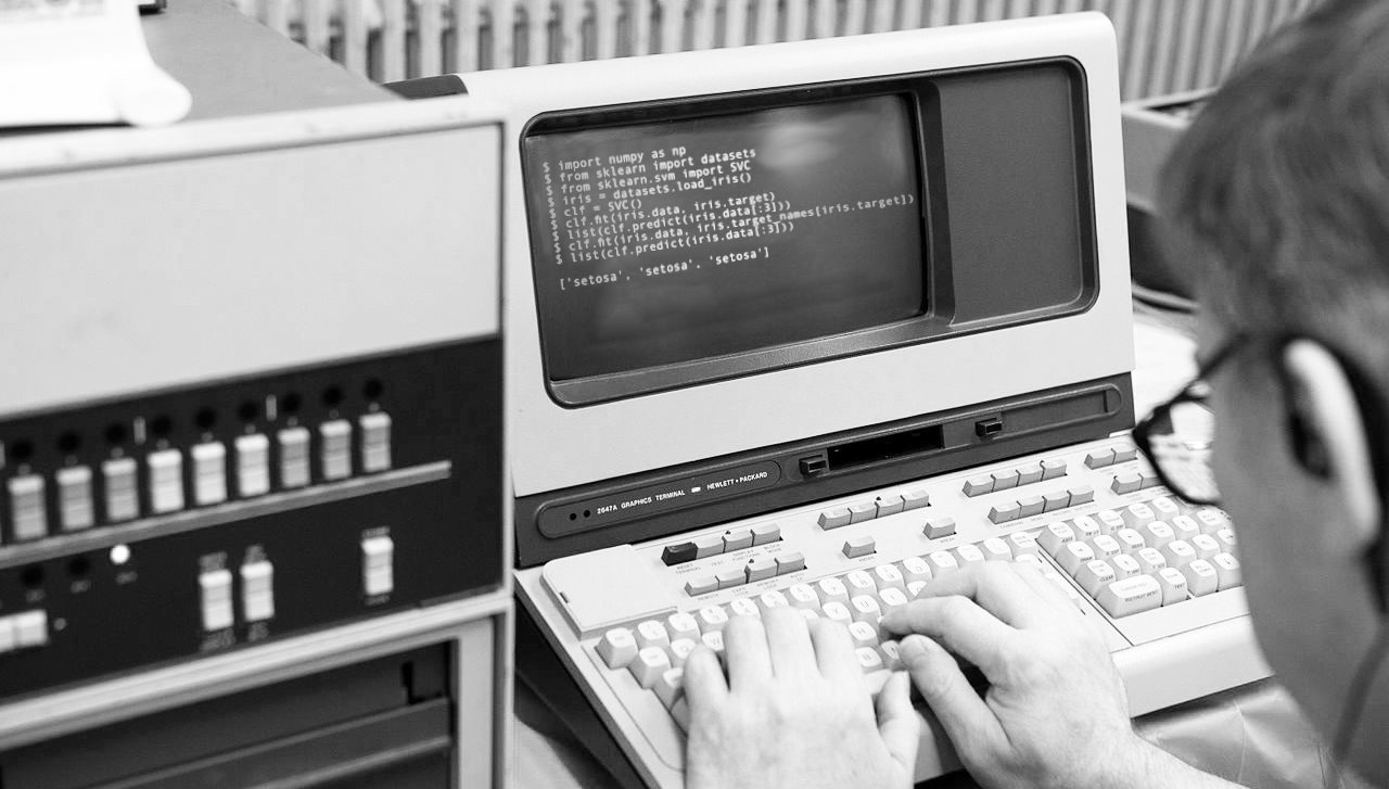 A picture of someone typing away on an old computer.